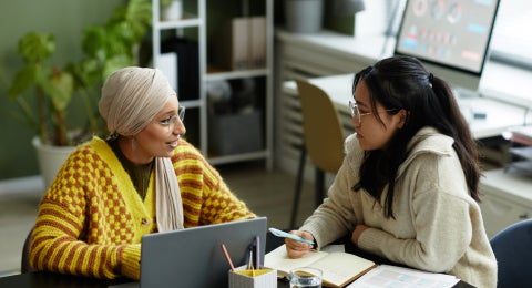 Portrait of two creative young women collaborating in business meeting while enjoying work in office.