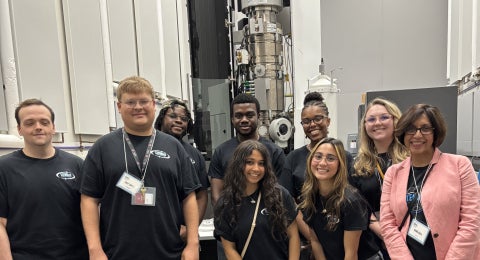 Dr. Rama Bala standing with a group of STEMnetX Fellows smiling at the camera in a science lab.
